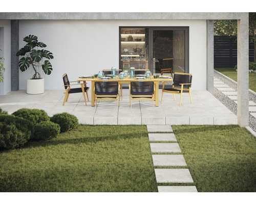 Gartenszene mit Esstisch und Stühlen auf einer Terrasse neben einem Rasen
