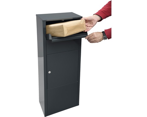Person legt Paket in einen Paketbriefkasten