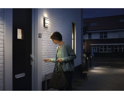 Frau schließt Haustür mit Außenleuchte auf