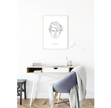 Schreibtisch mit Stuhl und gerahmtem Porträt an der Wand in einem hellen Raum.