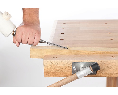 Eine Person benutzt einen Stechbeitel an einer Werkbank.