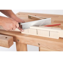 Handwerker sägt Holz mit einer Feinsäge und einer Schneidlade auf einer Werkbank