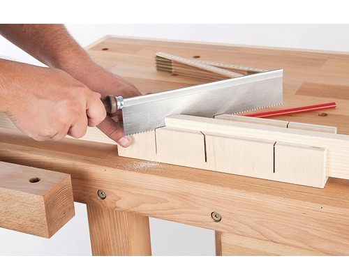 Handwerker sägt Holz mit einer Feinsäge und einer Schneidlade auf einer Werkbank