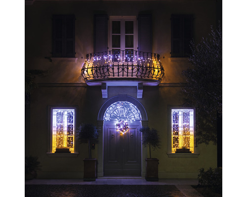 Hausfassade mit Weihnachtsbeleuchtung an Balkon, Fenstern und Eingangstür