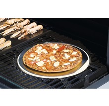 Auf einem Grill liegt eine Pizza auf einem Pizzastein, umgeben von Scampi.