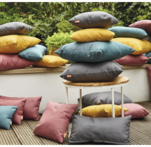 Szene mit gestapelten Outdoor-Kissen in verschiedenen Formen und Farben auf einer Terrasse