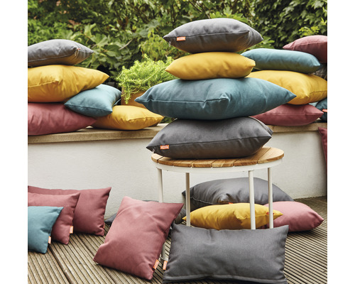 Szene mit gestapelten Outdoor-Kissen in verschiedenen Formen und Farben auf einer Terrasse