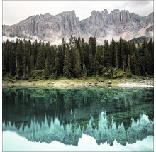 Bergsee mit Spiegelung von Bäumen und Bergmassiv im Wasser