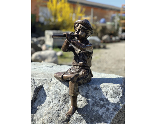 Bronzefigur eines Jungen, der auf einem Stein sitzend Flöte spielt, als Gartendekoration