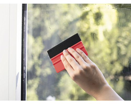 Hand reinigt Fenster mit einem Fensterwischer.