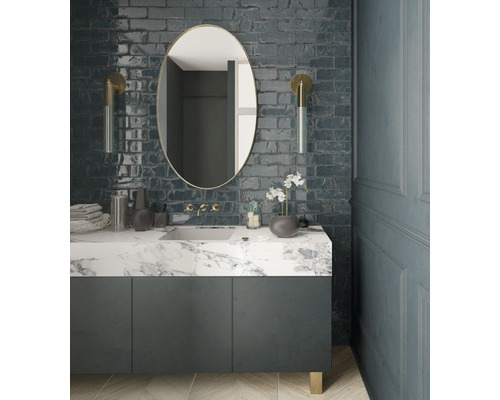 Modernes Badezimmer mit Waschtisch, Spiegel und Wandleuchten vor einer Ziegelwand.