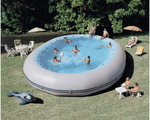Aufblasbarer Pool im Garten mit spielenden Menschen, umgeben von Gartenmöbeln.