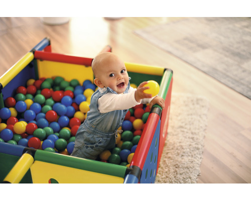 Fröhliches Baby in einem Spielhaus gefüllt mit Bällen.