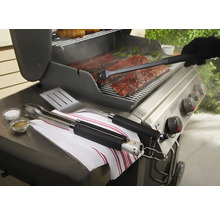 Grillszene mit Rippchen, Grillzange, Grillwender, Pinsel und Gewürzen auf einem Grill