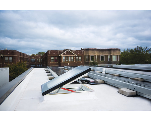 Aufnahme einer Dachterrasse mit Dachfenster und Solarpanelen.