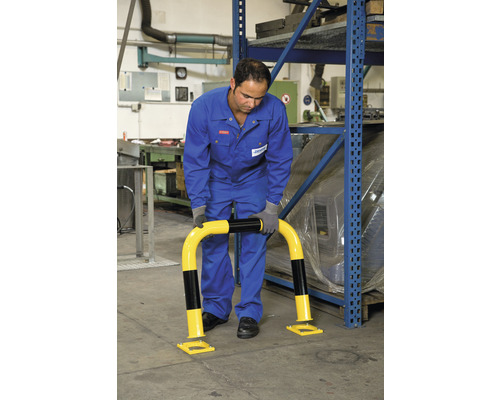 Mann montiert einen gelb-schwarzen Anfahrschutz vor einem Regal