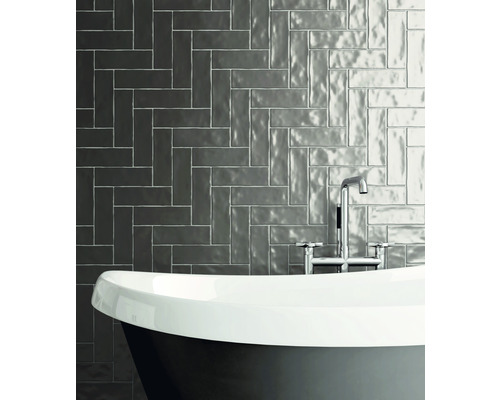 Badezimmer mit Badewanne und Wandfliesen im Fischgrätmuster