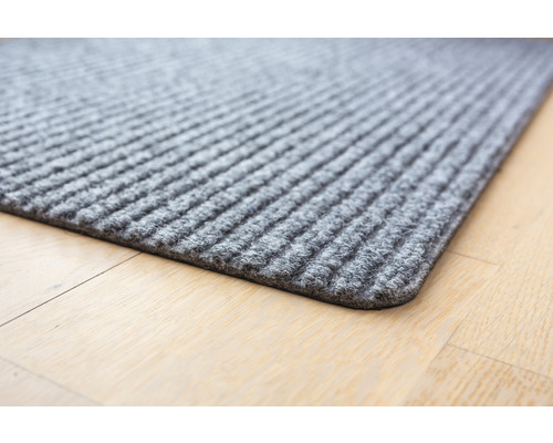 Graue Fußmatte mit gerippter Oberfläche auf Holzboden