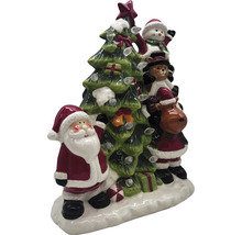 Weihnachtsdekoration mit Weihnachtsmann, Schneemann, Teddybär und Rentier neben einem Weihnachtsbaum mit Lichtern