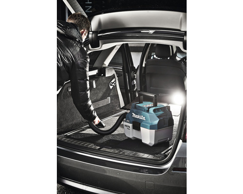 Mann saugt mit einem Makita Akku-Sauger den Kofferraum eines Autos aus.