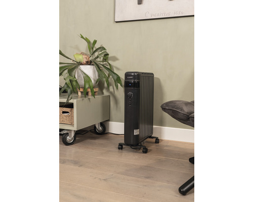 Schwarzer Elektro-Ölradiator im Wohnraum auf Holzboden