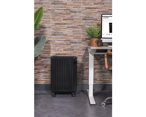 Schwarzer Ölradiator in einem Büroraum neben einem Schreibtisch.