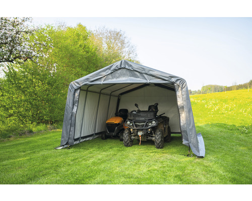 Graue Gerätegarage mit einem Rasenmäher und einem Quad im Garten