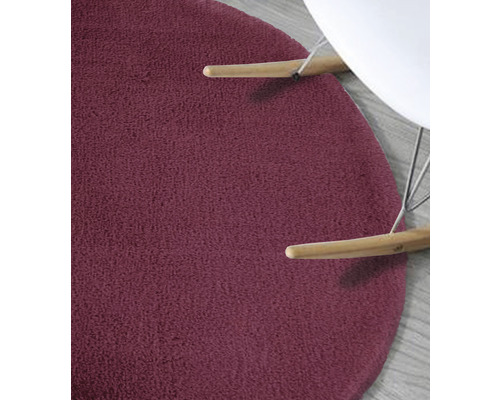 Detailansicht eines runden, texturierten Teppichs unter einem Stuhl