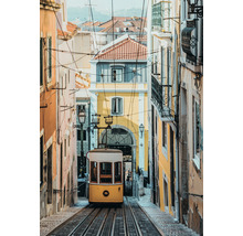 Gelbe Straßenbahn auf Schienen in einer Gasse mit Gebäuden