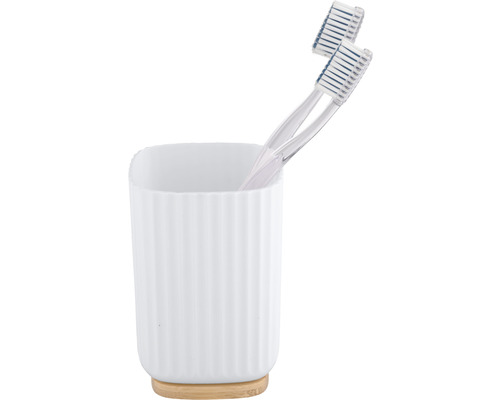Zahnbürsten in einem weißen Zahnbürstenhalter aus Keramik mit Bambusfuß