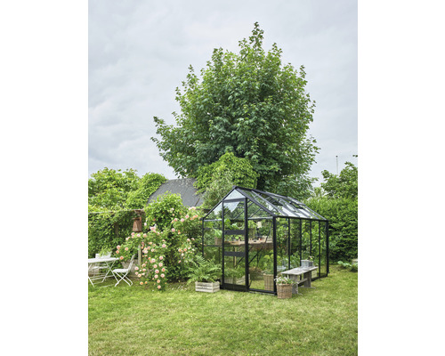 Gewächshaus im Garten mit Bepflanzung und Gartenmöbeln