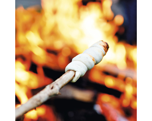 Stockbrotteig um einen Stock gewickelt, der über einem Lagerfeuer gebacken wird