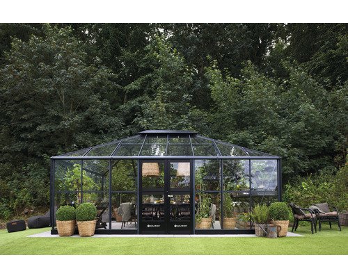 Gewächshaus mit Tisch, Stühlen und Pflanzen im Garten.