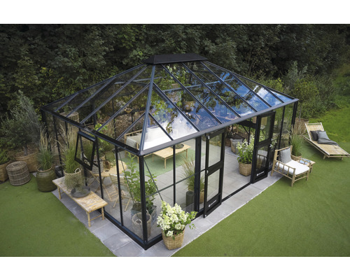 Gewächshaus mit Glaswänden und Metallrahmen im Garten.