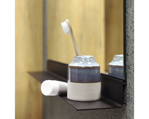 Badezimmerszene mit Zahnputzbecher, Zahnbürste und Kosmetikprodukt auf einem Regal