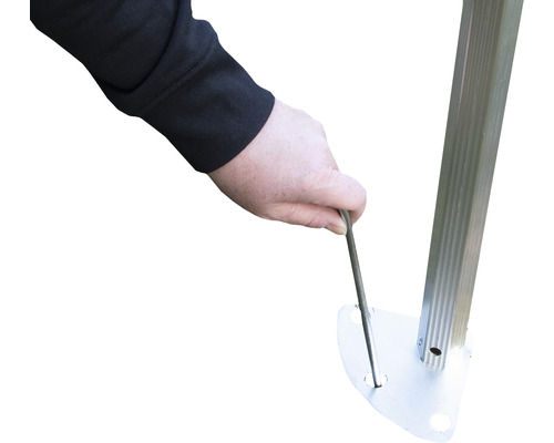 Eine Person befestigt mit einem Hering einen Pavillon am Boden.