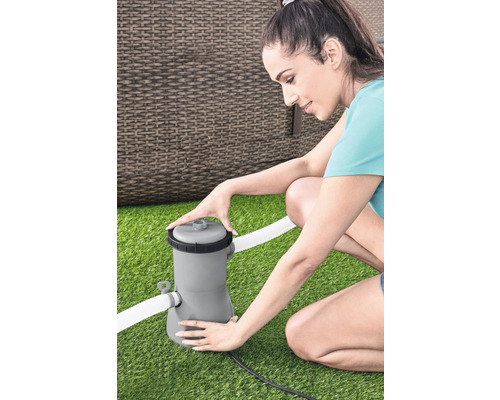 Frau installiert Poolfilteranlage auf Rasen