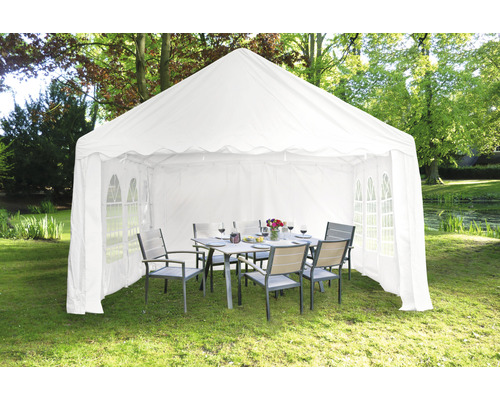 Weißes Partyzelt mit Tisch und Stühlen im Garten.