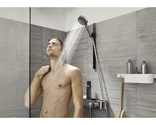 Mann unter einer Handbrause in einem modernen Badezimmer