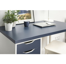 Detailansicht eines Schreibtisches mit dunkelblauer Platte, Schubladen, Laptop, Tasse und Dekoration