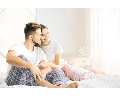 Paar sitzt im Schlafzimmer auf dem Bett