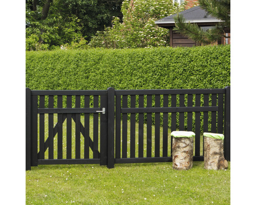 Schwarzer Holzzaun mit Gartentür und Baumstammhockern im Garten