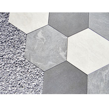 Sechseckige Bodenfliesen in verschiedenen Grautönen neben Kies