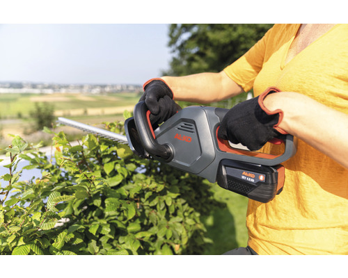 Frau benutzt Akku-Heckenschere von AL-KO zum Heckenschneiden