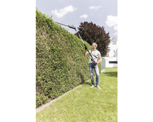 Mann schneidet Hecke mit einer Akku-Teleskop-Heckenschere im Garten.