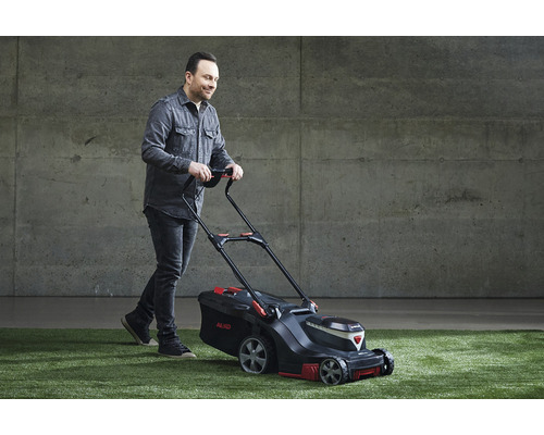 Mann schiebt Rasenmäher auf Rasenfläche