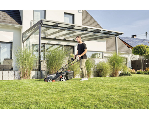 Mann mäht Rasen mit einem Rasenmäher im Garten.