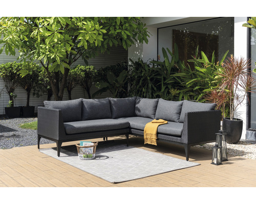 Graue Loungegruppe aus Rattan mit Kissen und Teppich im Garten