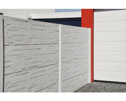 Betonzaun mit Strukturmuster neben einer Garage