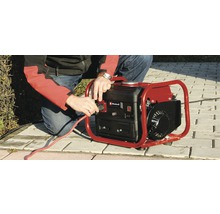 Ein Mann schließt ein rotes Stromkabel an einen Generator der Marke Einhell an.